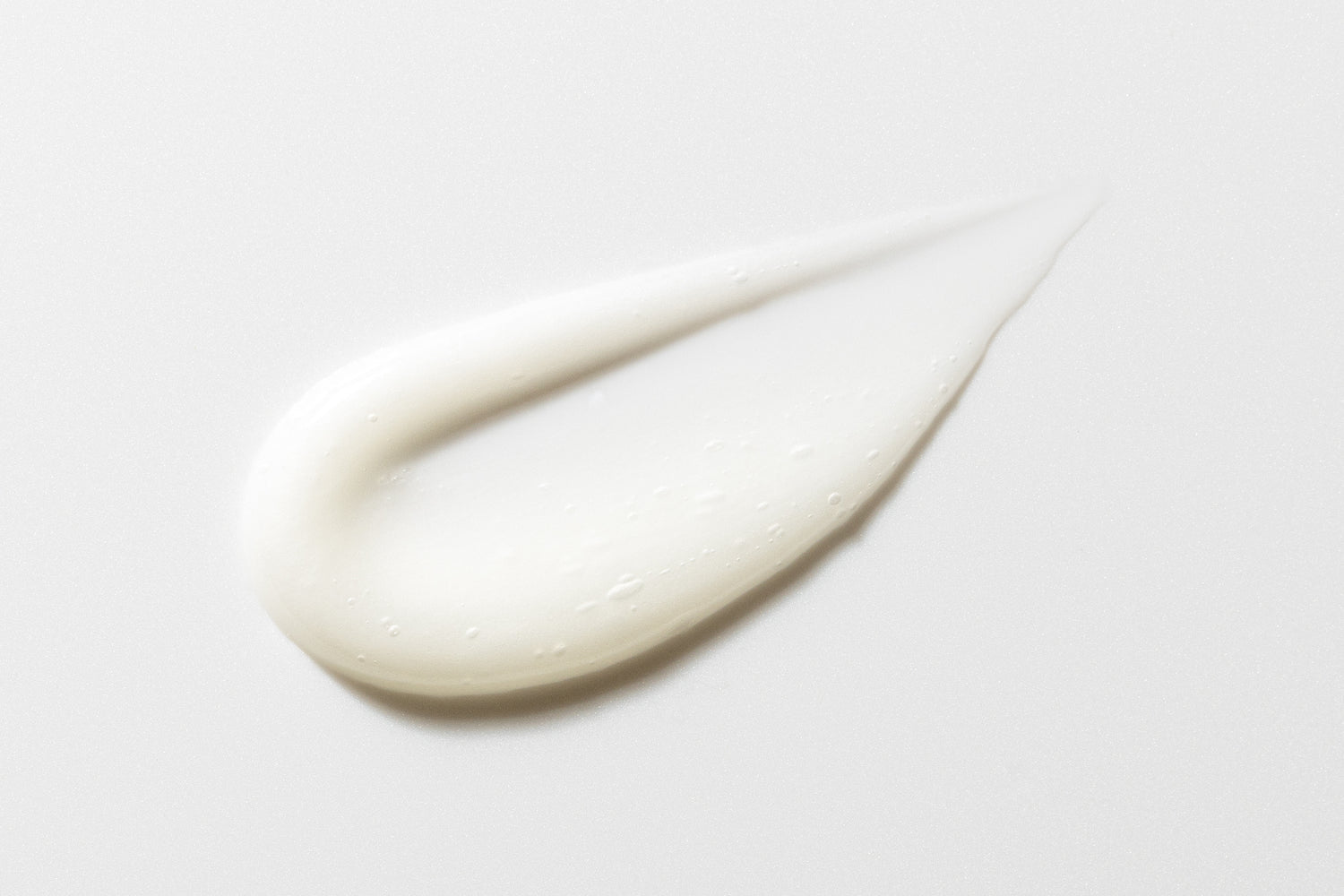 A smooth, creamy white substance in a curved shape on a white background.
