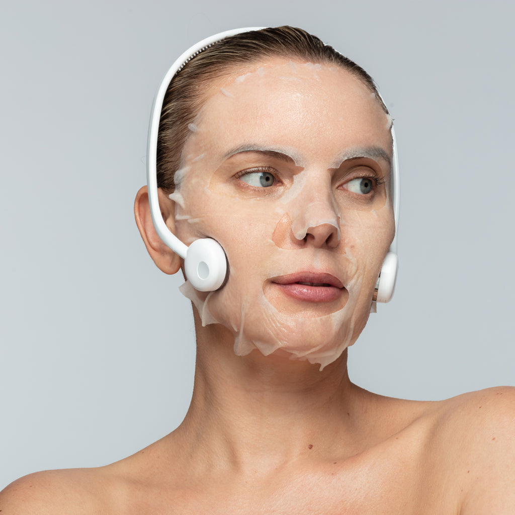 Person wearing a facial treatment mask and electronic skincare device.