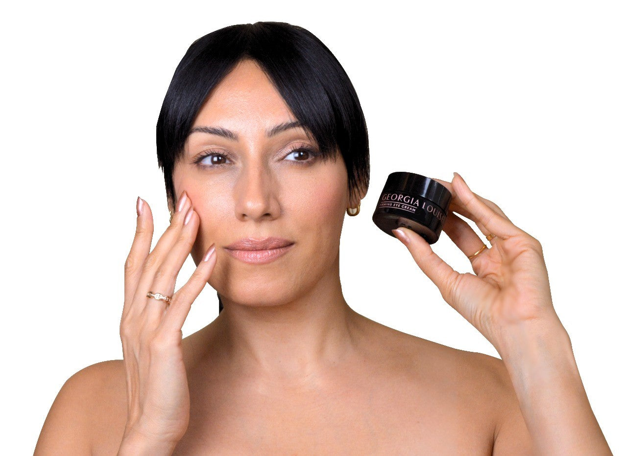 Woman applying skincare cream while holding a jar