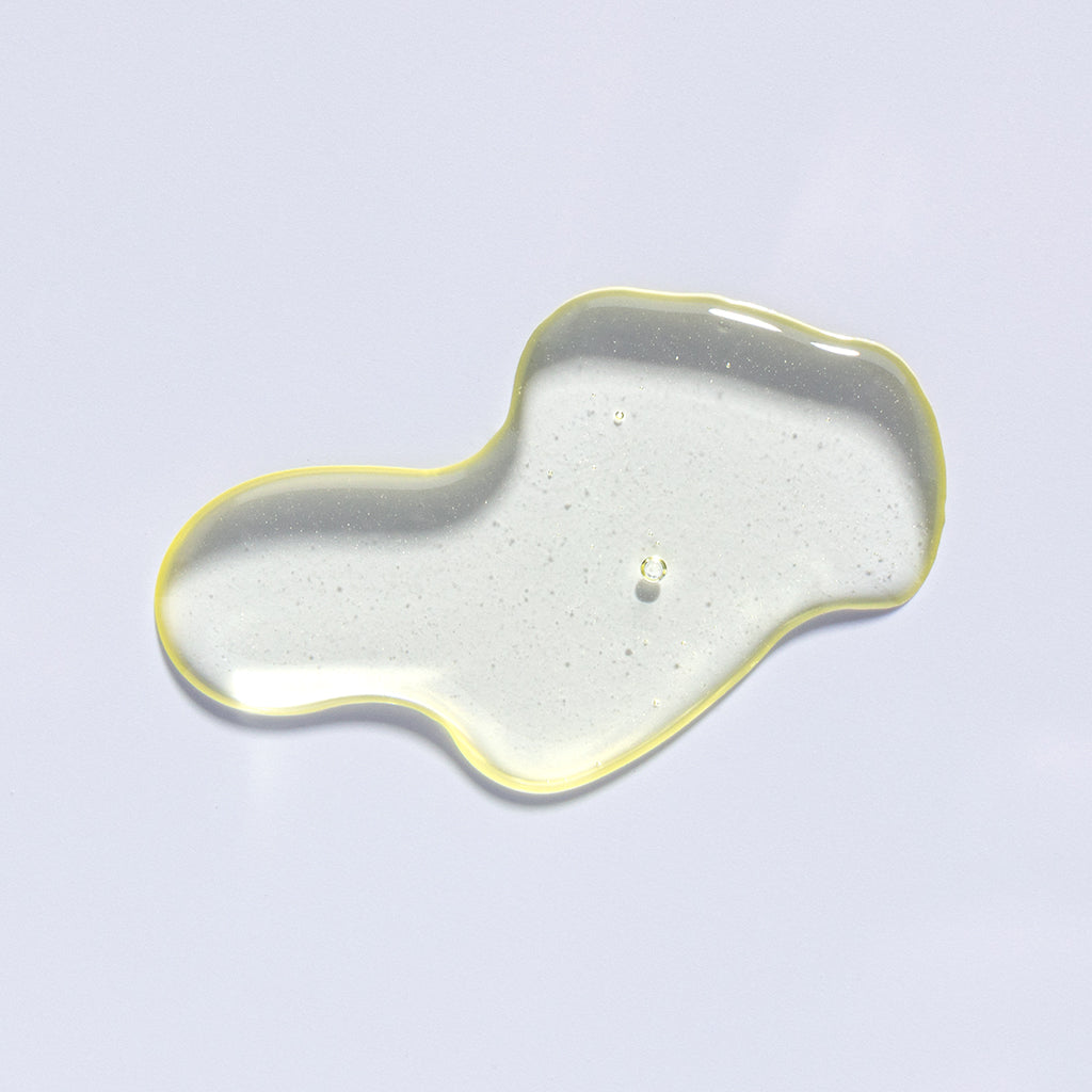 A glossy, translucent droplet of liquid with a yellow edge on a light background.