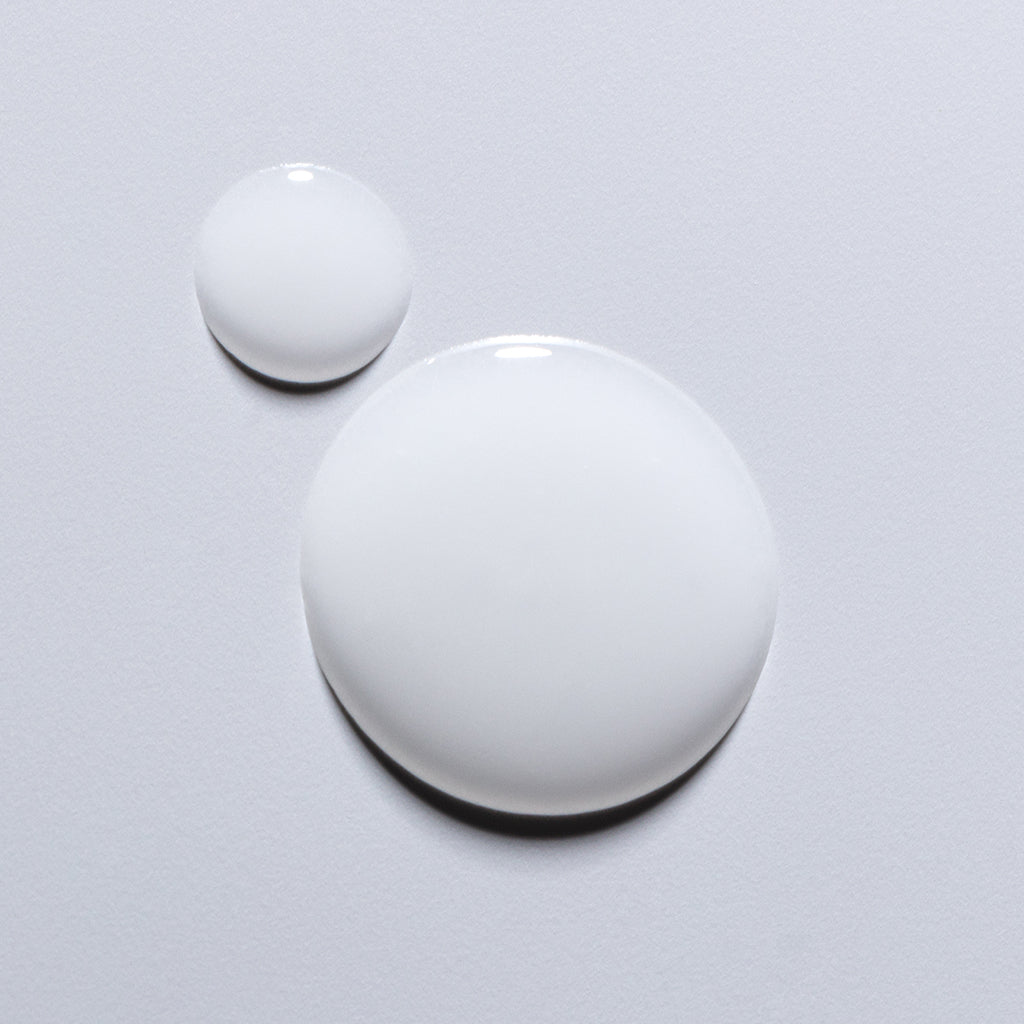 Two glossy white paint droplets on a light background.