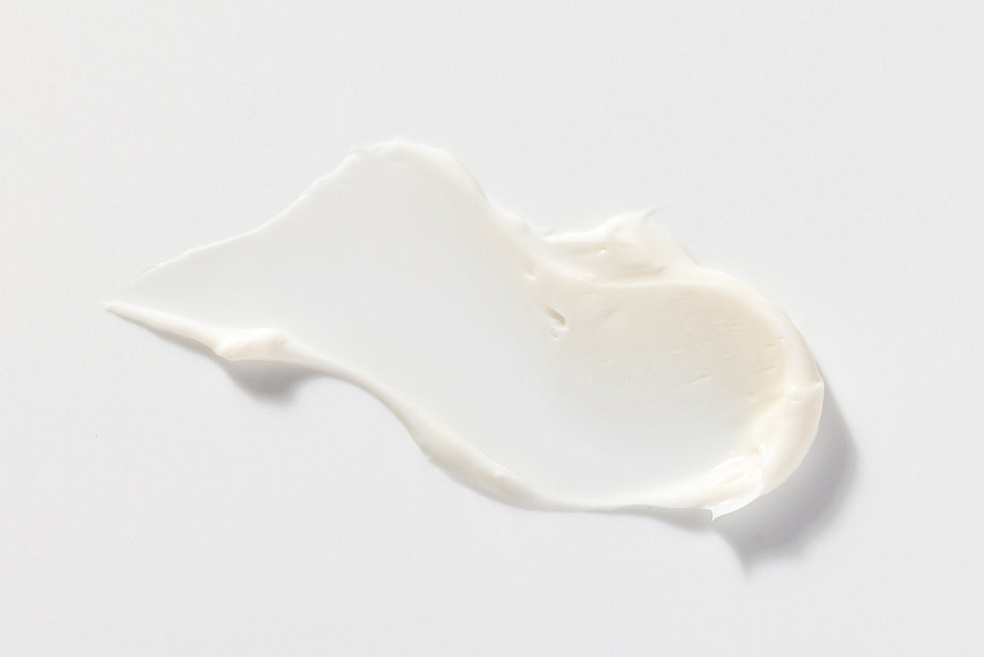 A smooth, creamy texture of white lotion spread on a surface.