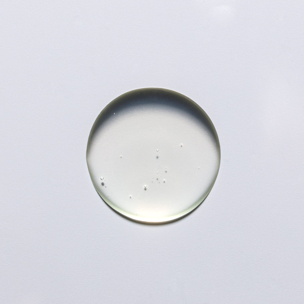 A clear, round droplet of liquid on a white surface.