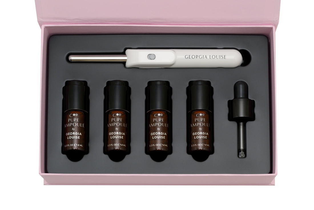 A beauty treatment kit with a microneedling pen and four serum vials in a pink box.